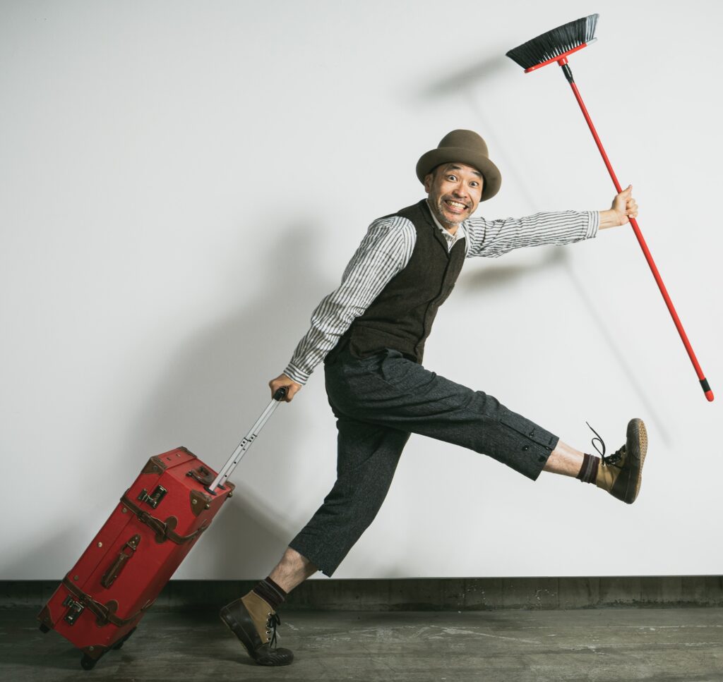 Japanese mime clown Ketch ex-Gamarjobat walking with his broom and suits case